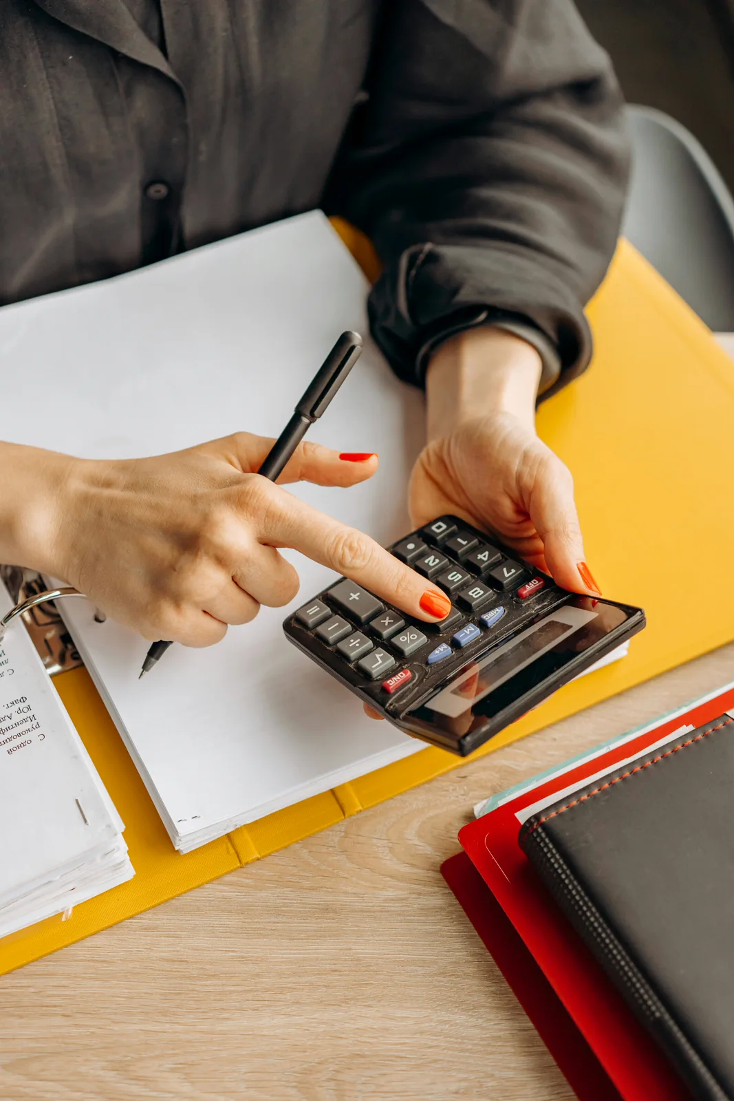 Consultor analisando documentos contábeis e fiscais em mesa de trabalho.